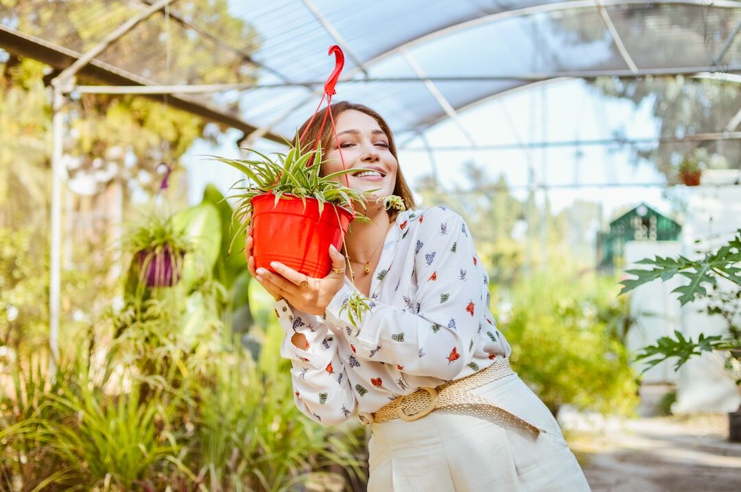 Latina woman gardener smiling while holding a small potted plant
