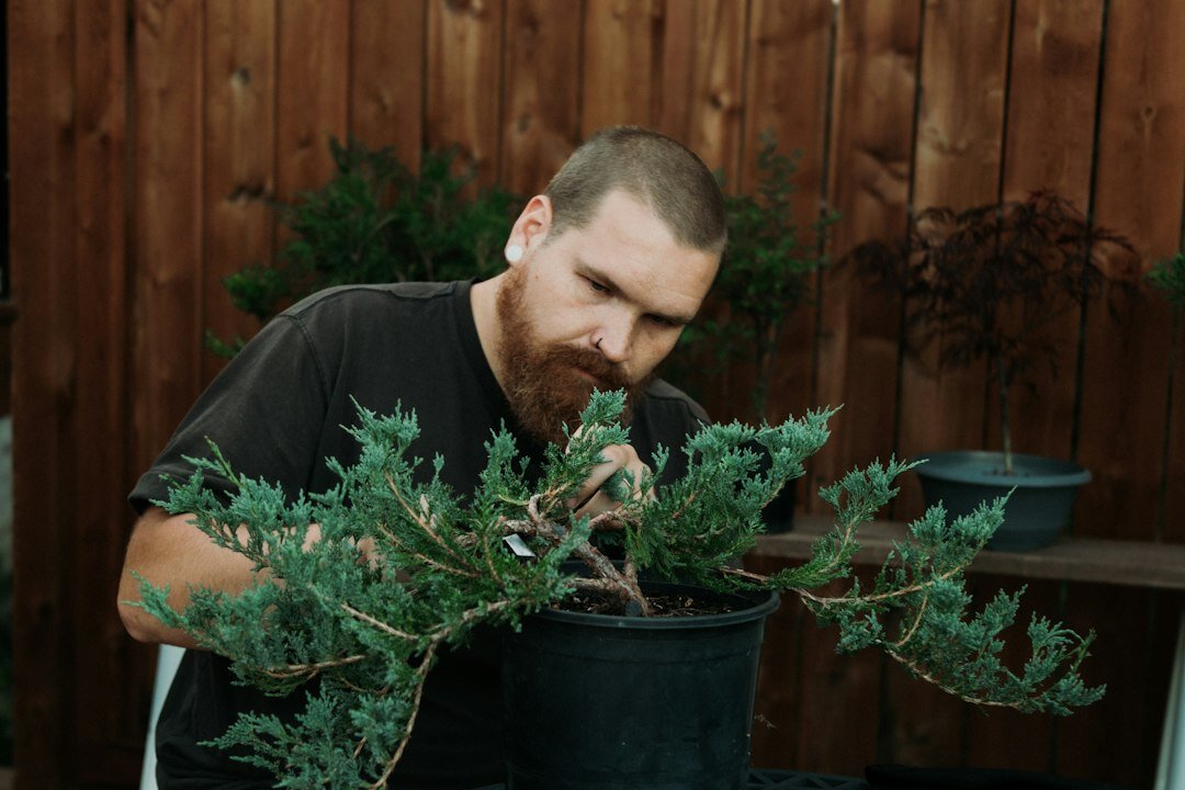 Uruguayan man gardener smiling while trimming a potted plant